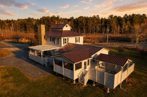 Wander between the covered porches and the pergola-shaded deck, each with its own seating for stepping outside. A short walk down the road takes you past the fields, right at the edge of the woods.