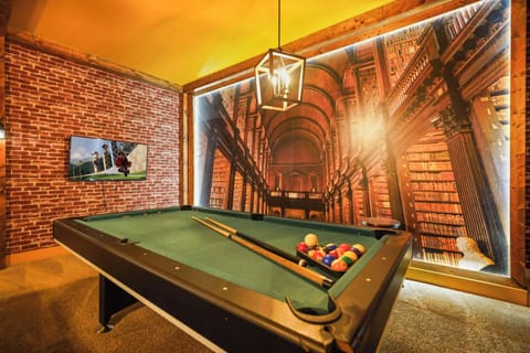 Enjoy a game of pool in this stylish game room featuring a grand library mural and modern amenities.