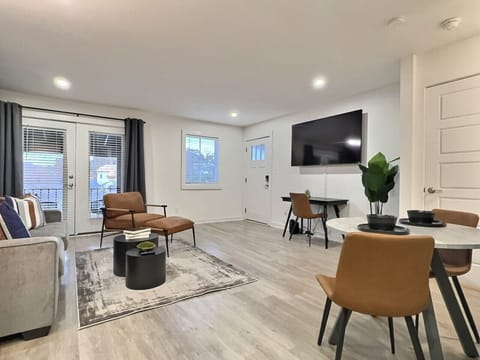 Bright and airy living area in this furnished apartment with comfortable seating, a TV, and a workspace, perfect for relaxing or staying productive.