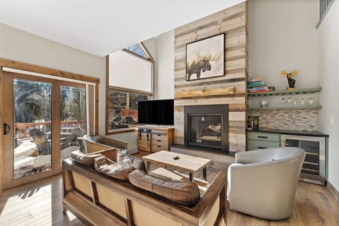 Unwind in your rustic-modern living room featuring a cozy fireplace, leather seating, and scenic forest views from every window.