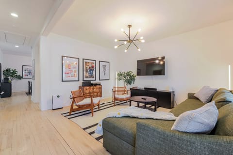 Sun-filled open living room with a sputnik chandelier and plush green sectional.