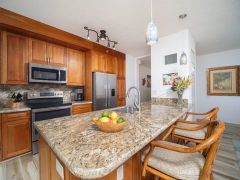 Cook and entertain in the spacious kitchen featuring granite countertops, modern appliances, and comfortable island seating for a family gathering.