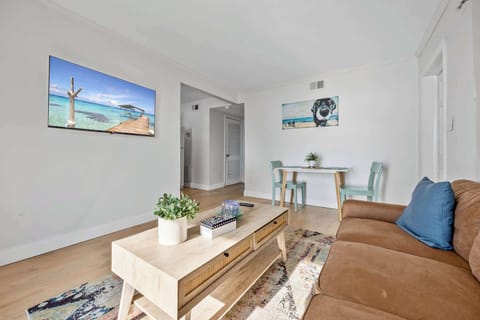 Modern living area with a leather sofa, wooden coffee table, and wall-mounted television.