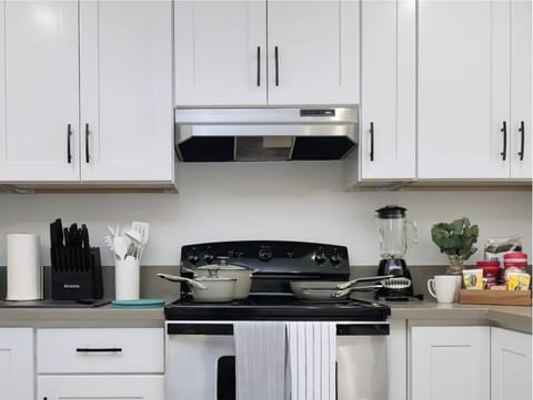 Clean and modern kitchen with white cabinets, stainless steel appliances, and a well-stocked counter