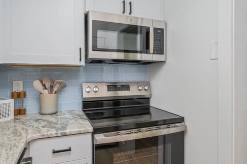 Sleek stove and microwave setup with stylish marbled countertop finish.