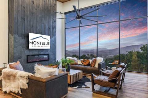 Modern living room with floor-to-ceiling windows showcasing mountain views at sunset.