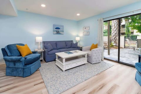 Bright living room with blue and white decor and sliding glass doors opening to a patio.