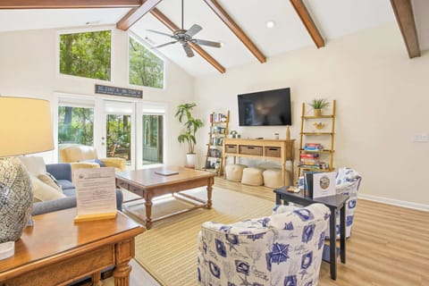 Living room with vaulted ceilings, wood beams, and large windows overlooking the greenery.