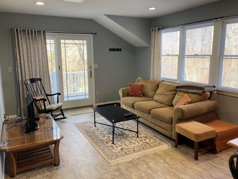 Main living area with couch, rocking chair, foot rests, and TV