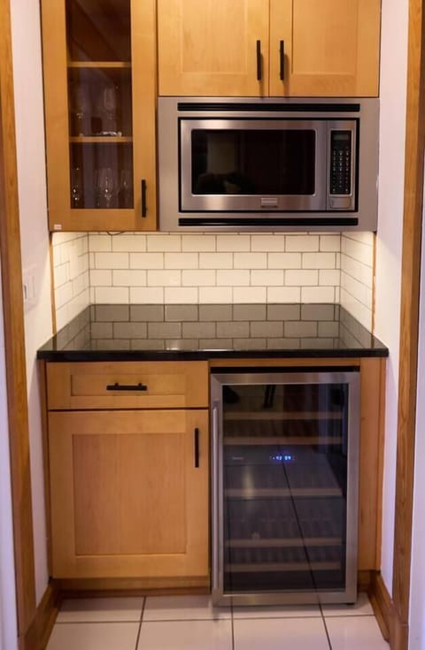 The bar hosts a wine fridge with separate settings for white and red wines along with wine glasses for 12.