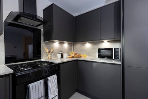 This modern kitchen features stylish cabinetry, bright under-cabinet lighting, and all the essentials for a convenient cooking experience.