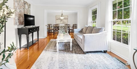 Relax in our bright, open-concept living room featuring hardwood floors, a Smart TV, and stylish furniture. Perfect for extended stays near Duke Medical Center, the space flows into a formal dining area for family meals