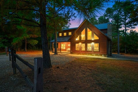 This cozy log cabin glows like a warm welcome in the piney woods, perfect for a peaceful getaway surrounded by those gorgeous old trees.