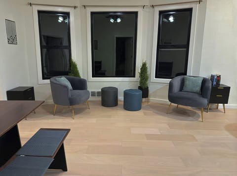 Bright seating area by large windows with cozy chairs and ottomans, perfect for relaxing.