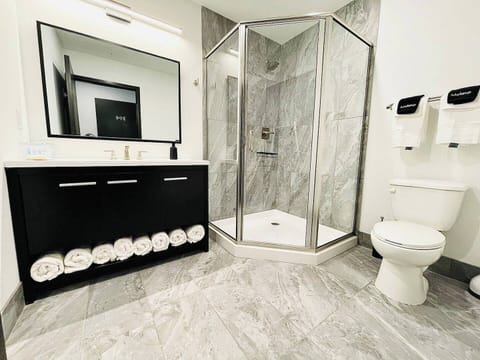 A pristine bathroom featuring a walk-in shower with elegant gray tiles, fresh towels, and modern amenities.

