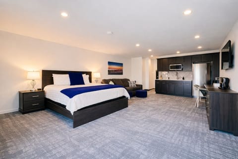 A bright, open room featuring a comfortable bed, work desk, ample storage, and a large TV, perfect for relaxing or working during your stay.