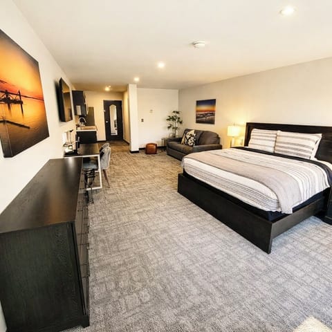 A bright, open room featuring a comfortable bed, work desk, ample storage, and a large TV, perfect for relaxing or working during your stay.