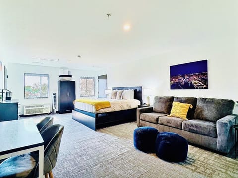 A bright, open room featuring a comfortable bed, work desk, ample storage, perfect for relaxing or working during your stay.