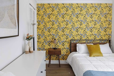 Wake up inspired in this bedroom with bright yellow wallpaper and cozy textures.