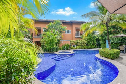 A vibrant community pool area featuring tables and seating for outdoor dining, a dedicated BBQ area for grilling, and a relaxing jacuzzi.