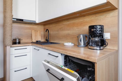 A modern kitchen with white cabinets, wooden countertops, and built-in appliances.
