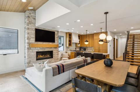 Bright open living space with a cozy fireplace, modern kitchen, and spacious dining area—perfect for gathering and relaxing in comfort.
