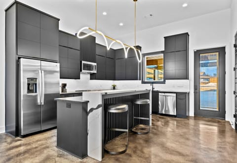 This modern kitchen combines sleek cabinetry, bold gold lighting, and a spacious layout, creating a stylish hub for cooking and entertaining.