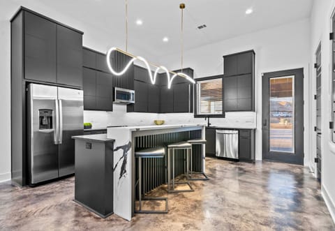 This sleek, modern kitchen combines minimalist cabinetry, bold gold lighting, and a spacious island, creating a chic and functional workspace.