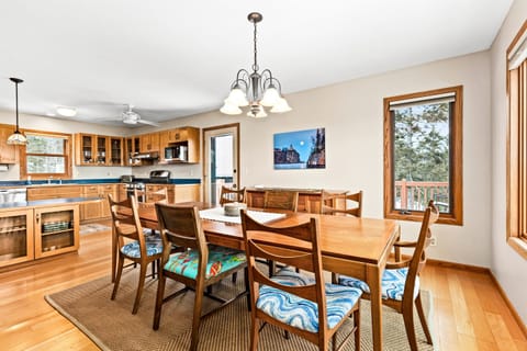Inviting dining room with a spacious table for family meals, open to the cozy living room just steps away. The layout creates a warm and connected space, with large windows filling the area with natural light and offering glimpses of Lake Superior.