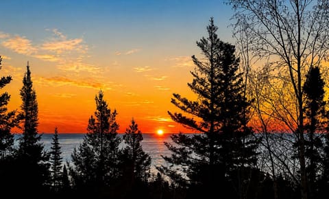 Wake up slowly at Treetops and step out onto the deck with a warm cup of coffee in your hand as the sun begins to rise over Lake Superior. The first light peeks through the trees, glowing softly between the branches before spilling out across the water.