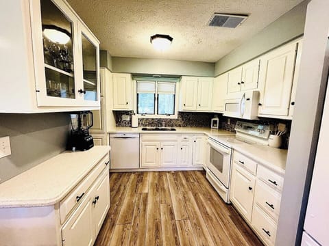 A spacious and bright kitchen with classic white cabinets, modern appliances, and a cozy layout, ideal for preparing family meals.