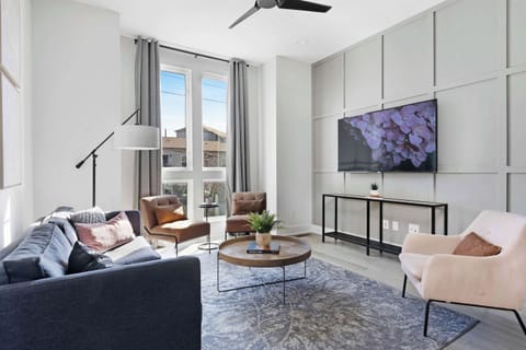 Inviting living room with a wall-mounted smart TV, a sleek leather couch, a stylish coffee table, and three accent chairs, creating a cozy and comfortable space.