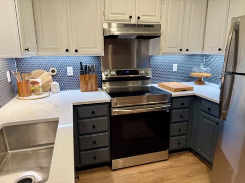 Fully stocked kitchen with utensils, pots, pans, glasses, cups, and dishwasher.
