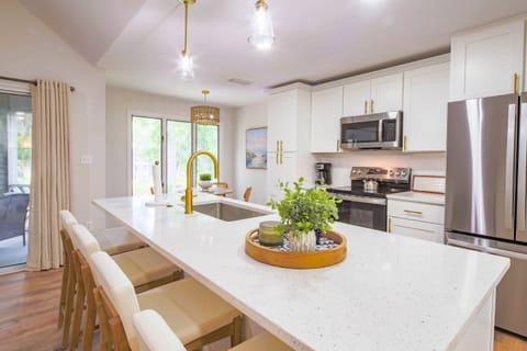 The brand new kitchen features white cabinetry, stainless steel appliances and gold hardware.