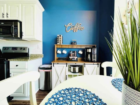 A charming white dining table set for four, placed near expansive windows. The balcony doors flood the area with natural light and provide a seamless indoor-outdoor experience.