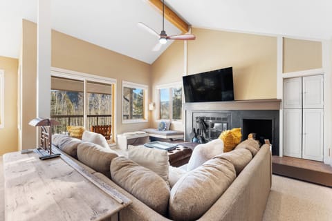 Sink into plush sofas by the crackling fireplace while mountain views frame your perfect retreat through soaring windows.