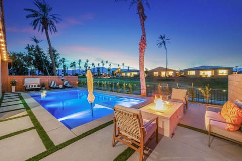 Evening-lit poolside w/ firepit, lounge chairs & warm ambiance for nights outdoors