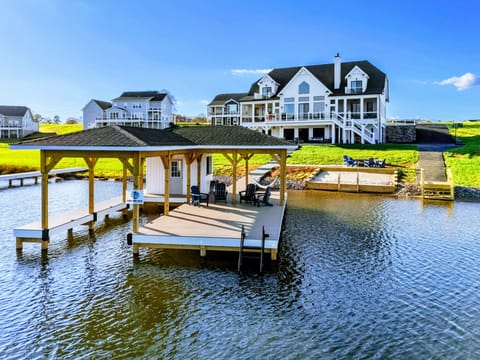 Lakeside property featuring a spacious house with outdoor amenities, a private dock, and a sandy beach area.