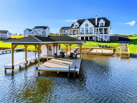 Lakeside property featuring a spacious house with outdoor amenities, a private dock, and a sandy beach area.