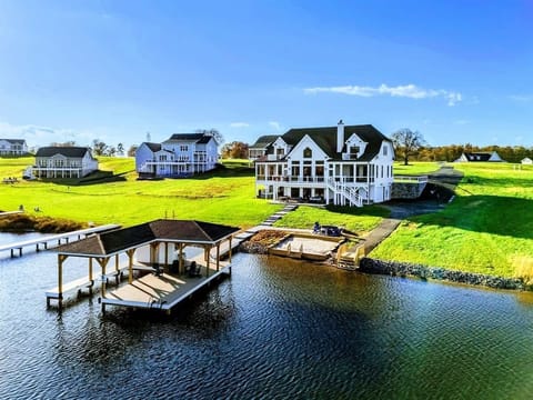 Lakeside property featuring a spacious house with outdoor amenities, a private dock, and a sandy beach area.