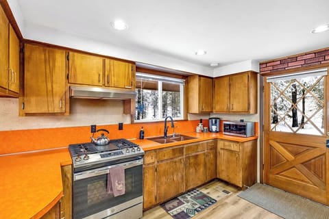 A vintage kitchen with wooden cabinets and a snowy window view.