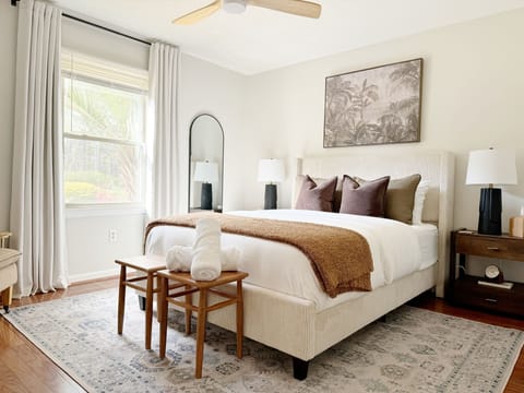 This bright and sunny bedroom boasts large windows and a cozy bed. 
