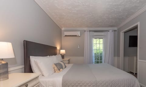 Gray walls and white trim frame a king bed with white linens and a textured gray quilt in the bedroom.