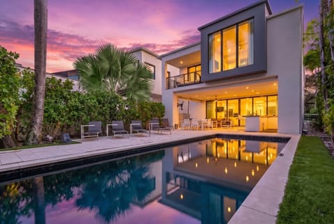 Contemporary glass-front villa with private swimming pool, outdoor dining patio, and second-story viewing balcony