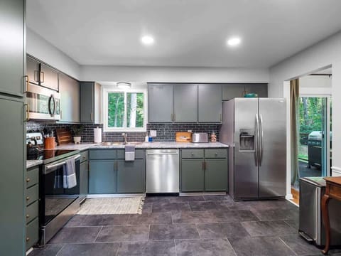 Fully equipped modern kitchen featuring sleek grey cabinets, stainless steel appliances, and a walk-out to the patio. 🍽️🌳