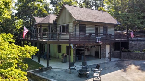 Features an upper deck, covered patio, basketball hoop, seating, and scenic forest views.