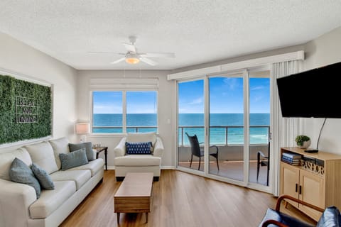 Living room with wall mounted smart tv,  leather sleeper sofa, 2 leather arm chairs, access to the beachside balcony and an AMAZING Gulf view
