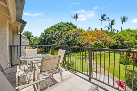 The private balcony overlooks manicured gardens with tropical blooms and towering palms, offering a peaceful retreat where you can enjoy morning coffee or evening relaxation surrounded by lush greenery.