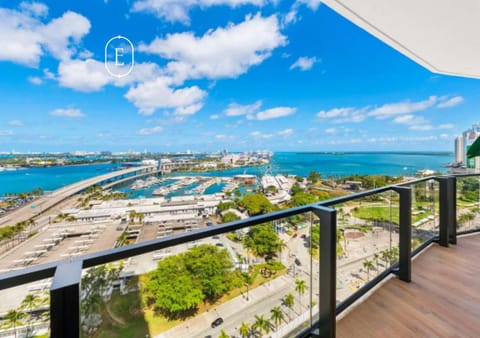 Scenic balcony view overlooking marina, blue ocean, and city skyline.