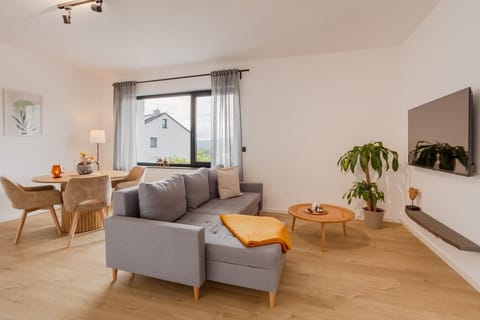 Heller Wohnbereich mit gemütlichem Sofa, Smart-TV, Essplatz und angenehmer Wohlfühlatmosphäre.